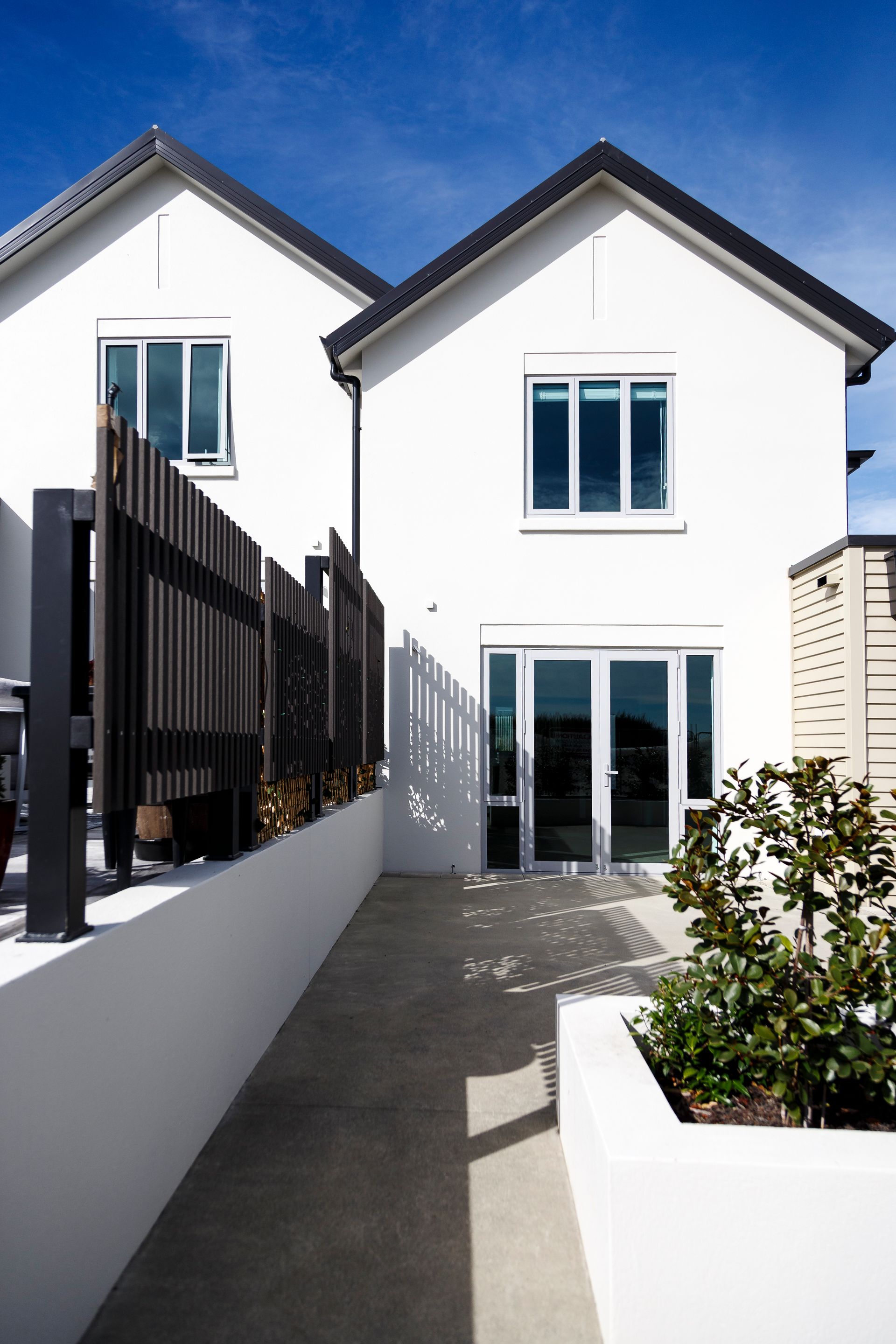 A white house with a black roof and a walkway leading to it