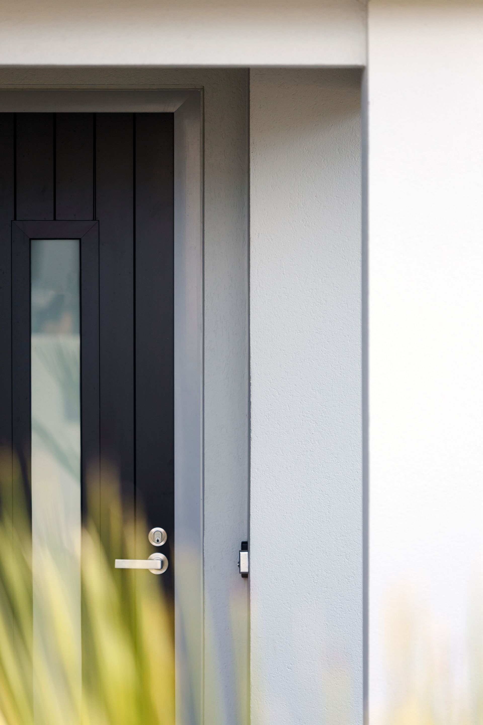 A close up of a black door with a glass window on a white wall.