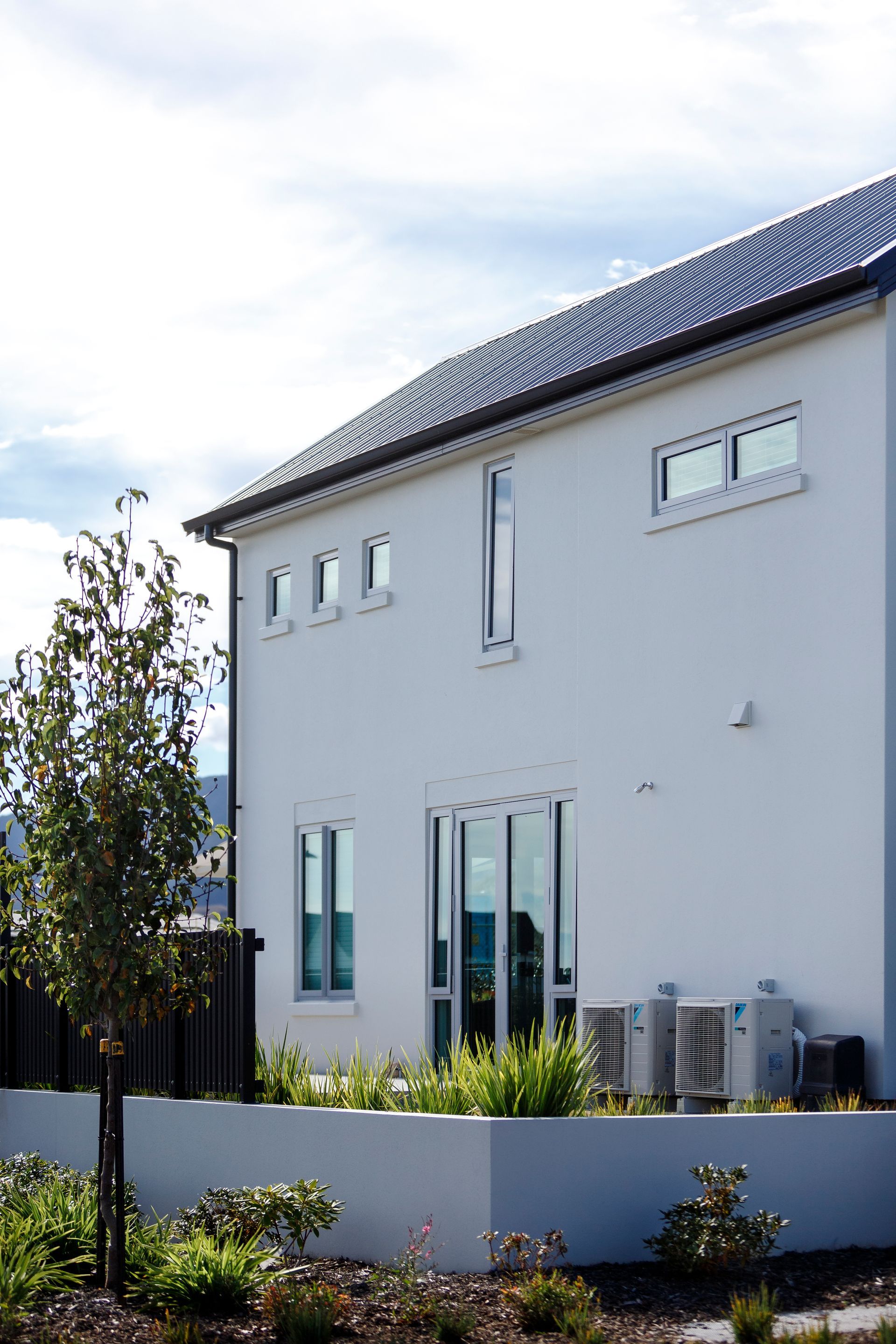 A white house with a roof that has solar panels on it
