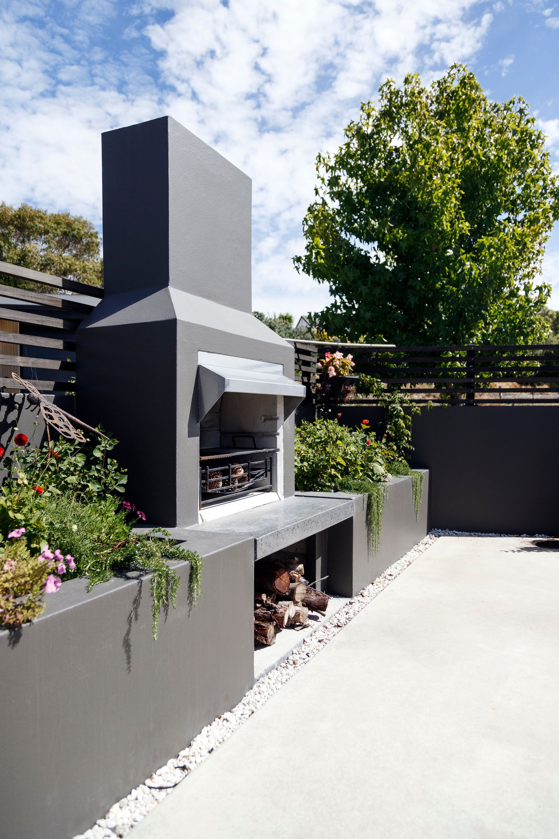 There is a fireplace in the backyard with a tree in the background.