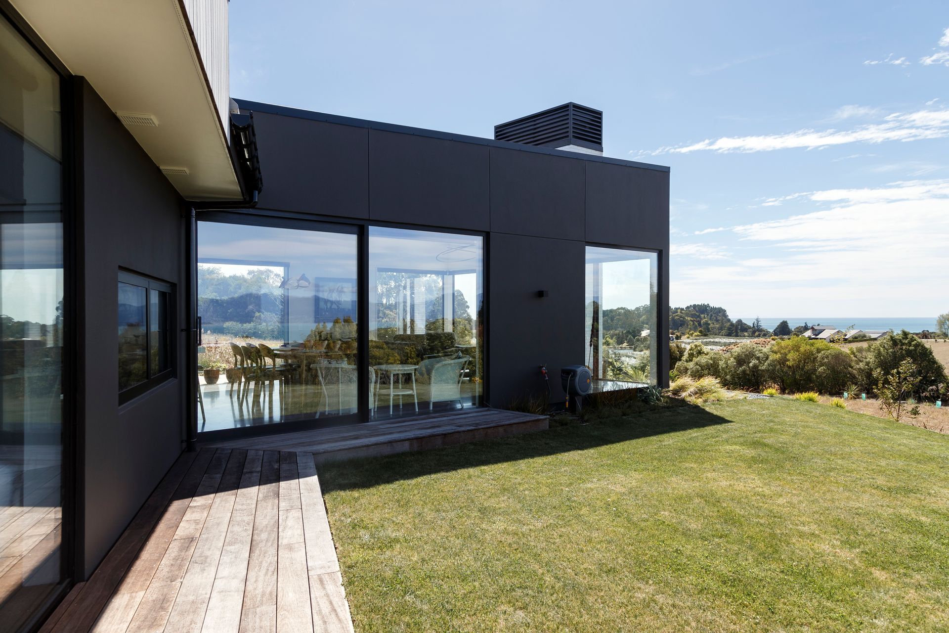 A modern house with a lot of windows and a large lawn in front of it.