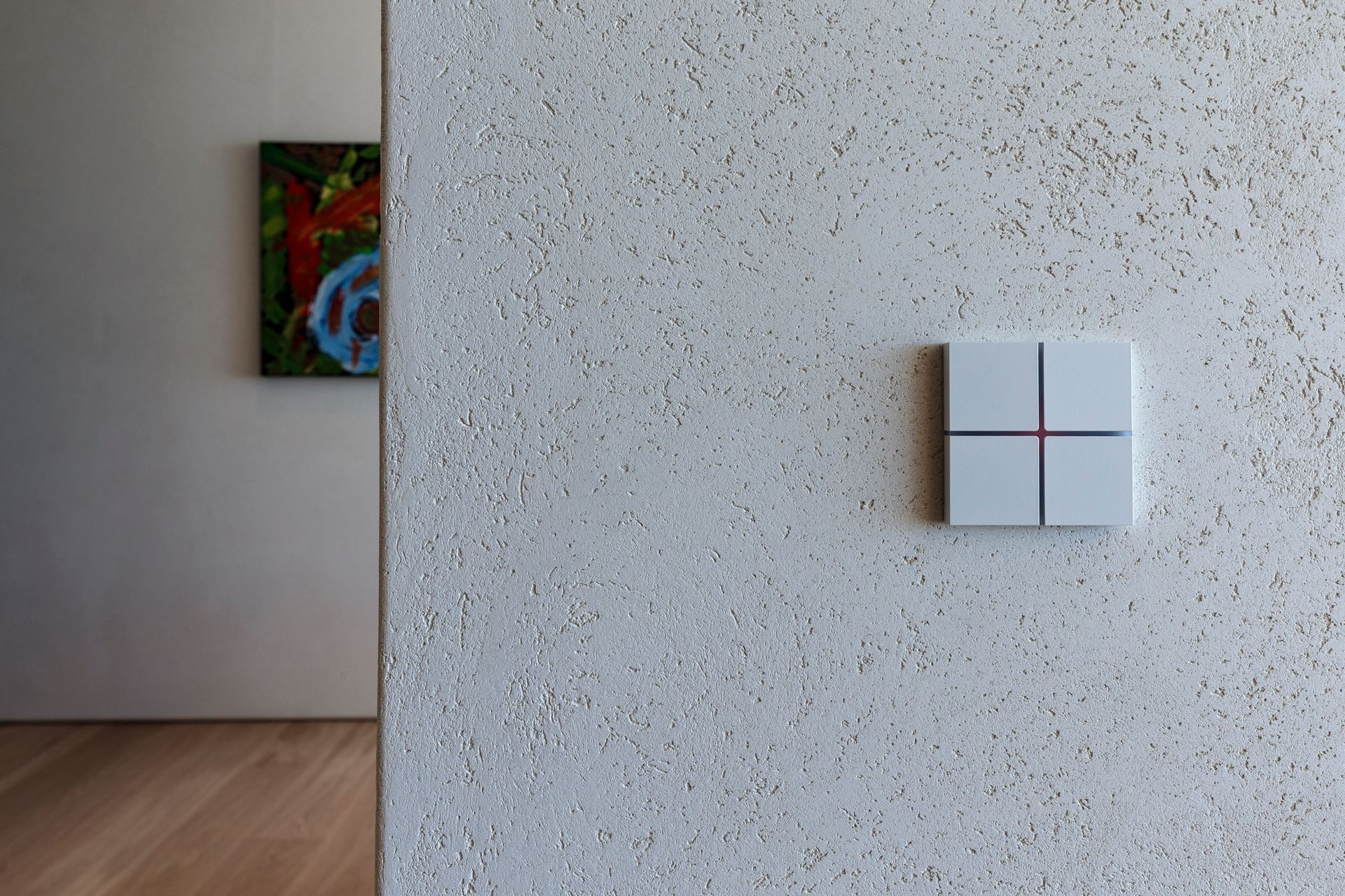 A white light switch on a white wall next to a painting on the wall.