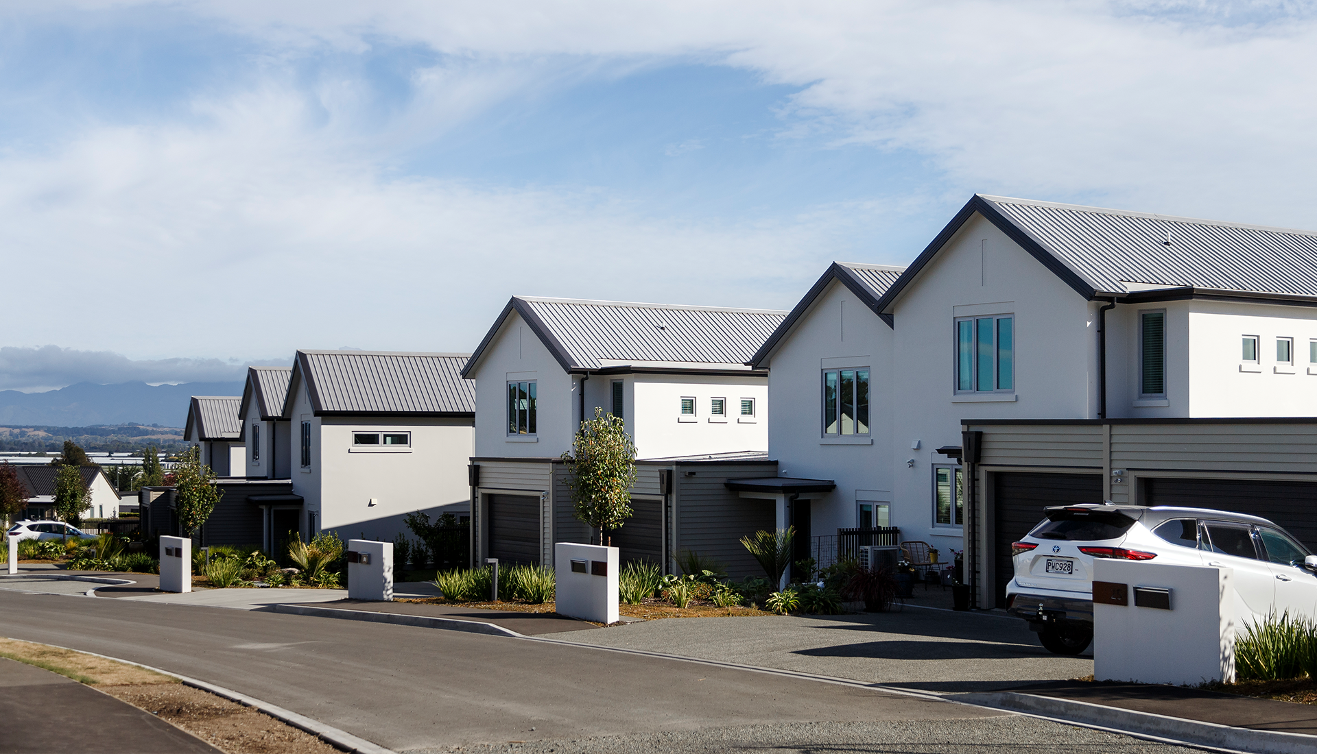 A row of houses with cars parked in front of them on a sunny day.