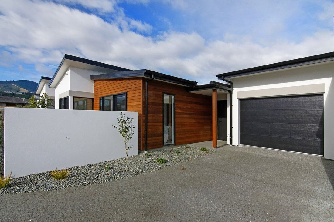 A house with a garage and a white wall in front of it.