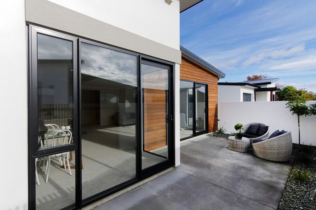 A modern house with a patio and sliding glass doors.