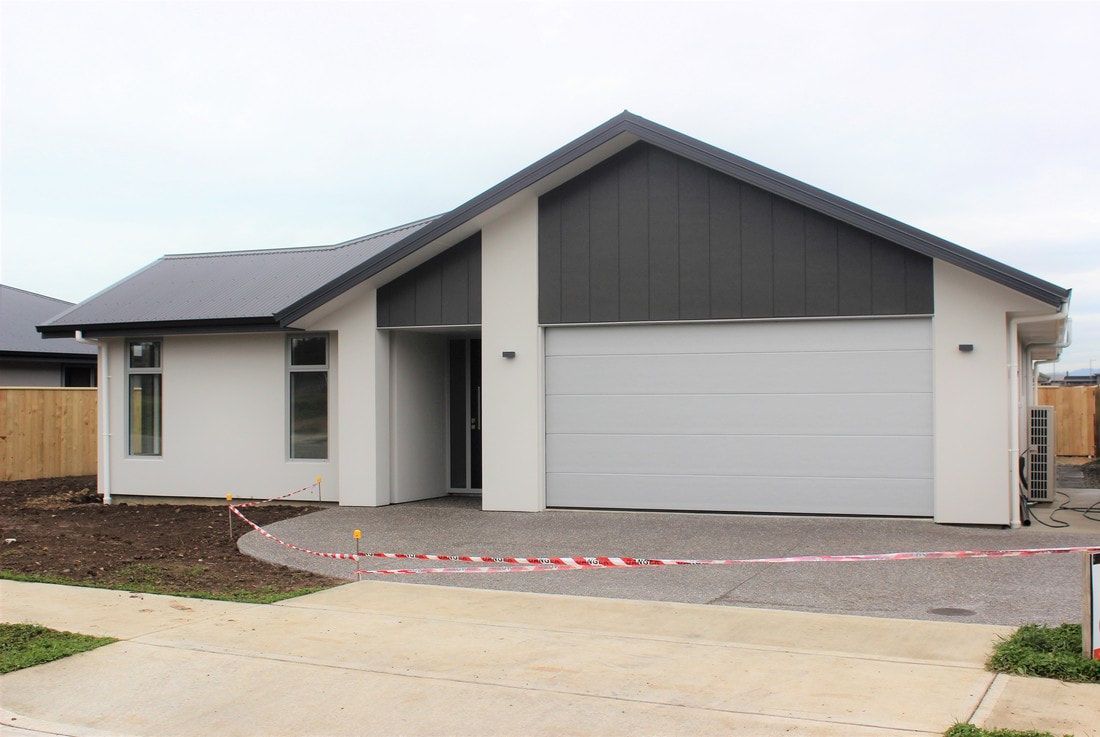 A white house with a black roof and a white garage door.
