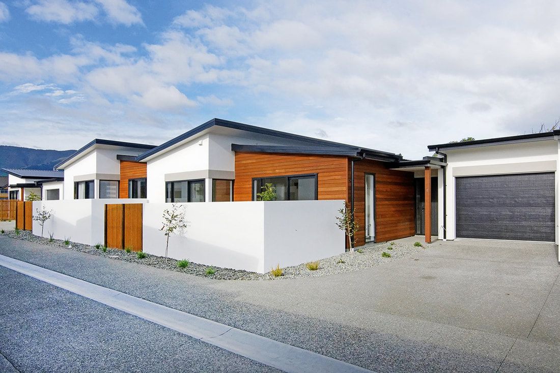 A row of white houses with wooden trim and a garage.