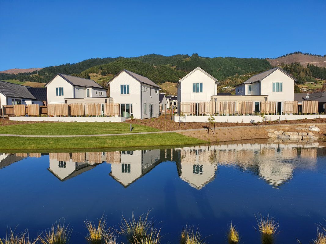A row of houses sitting next to a lake with mountains in the background.