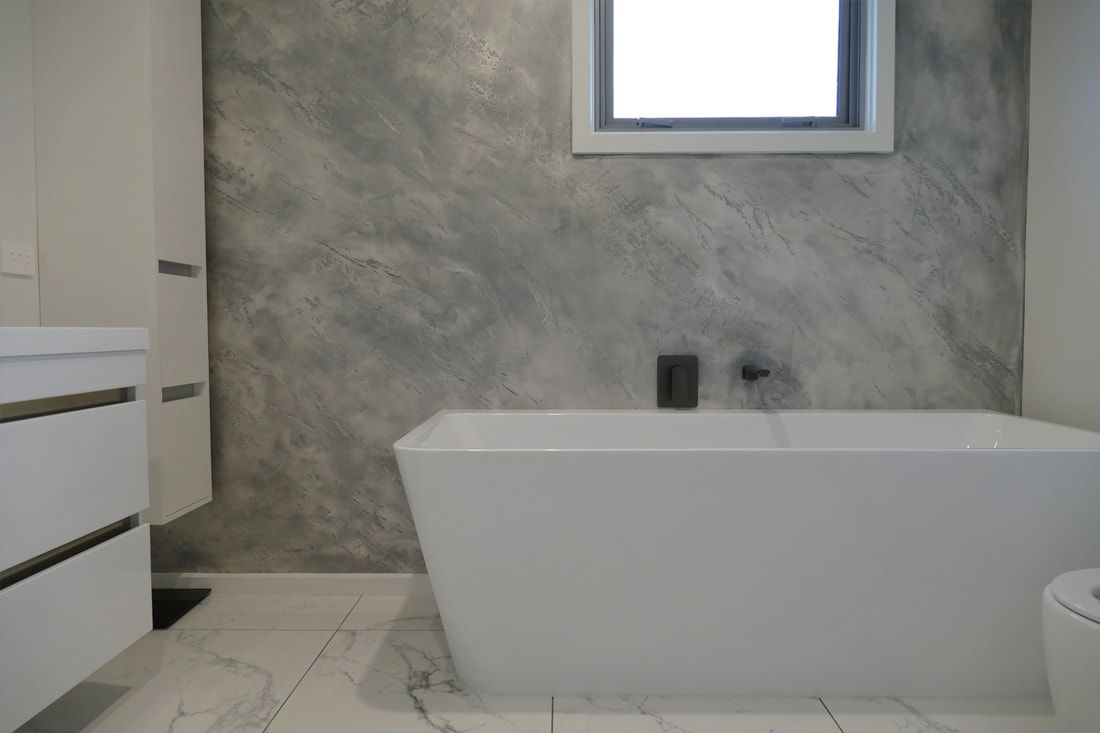 A bathroom with a bathtub , sink , and window.