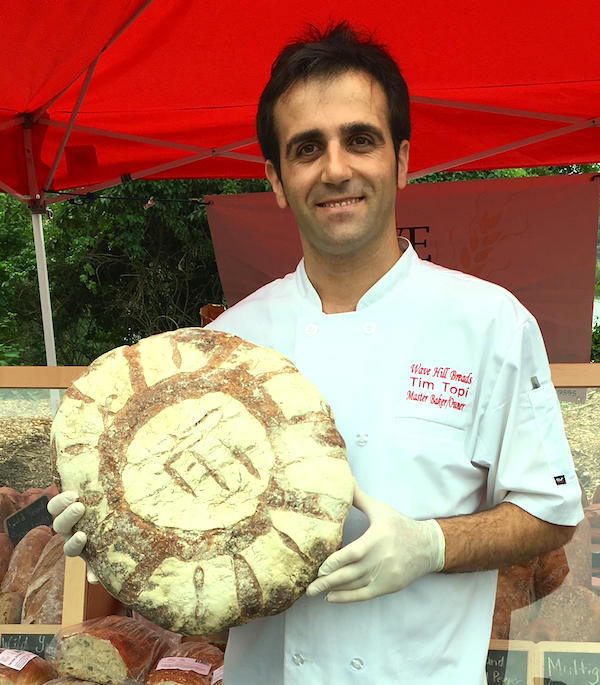 Master Baker Tim Topi is holding a loaf of bread with the letter t on it