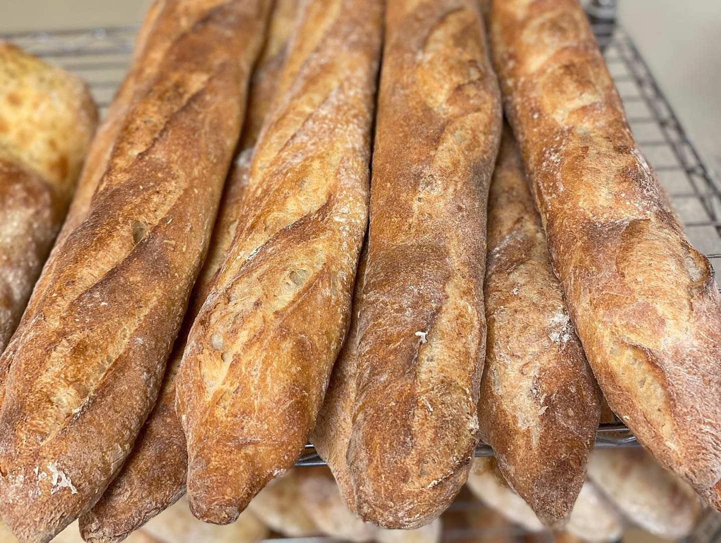 A bunch of baguettes are sitting on a cooling rack.
