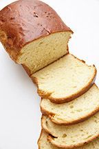 A loaf of bread is cut into slices on a white plate.