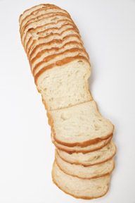 A loaf of sliced bread is sitting on a white surface.