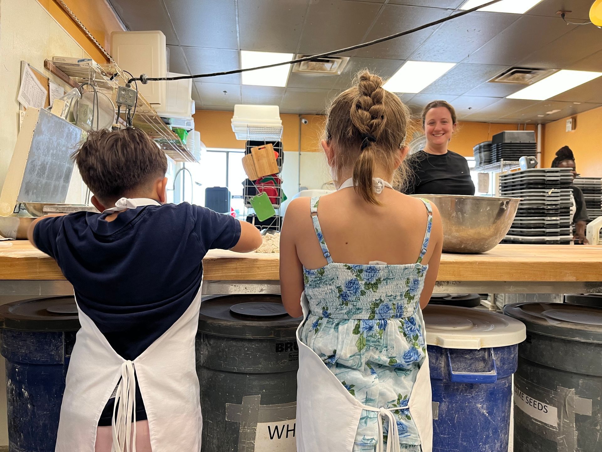 A boy and a girl are standing at a counter in a kitchen