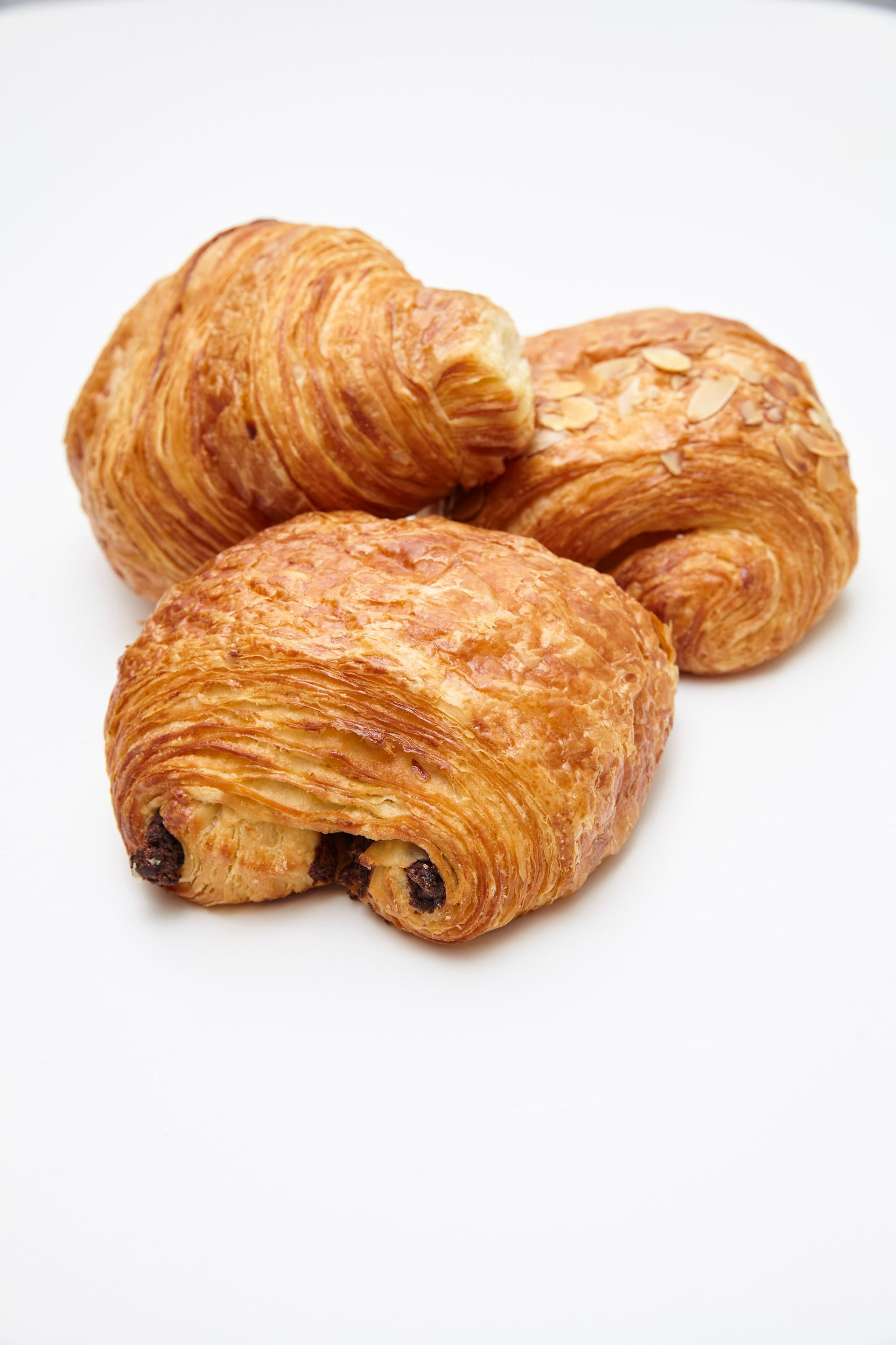 Three pastries are on a white plate and one has a bite taken out of it