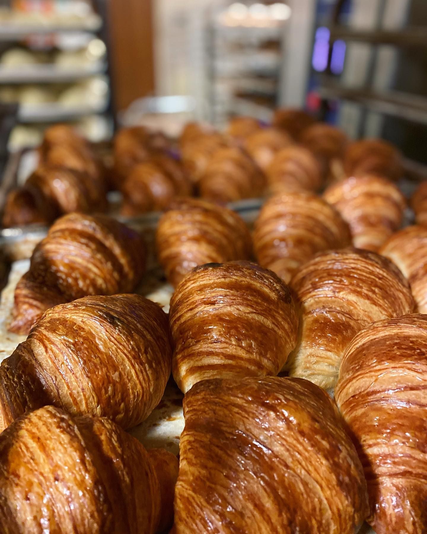 A bunch of croissants are sitting on a table in a bakery.