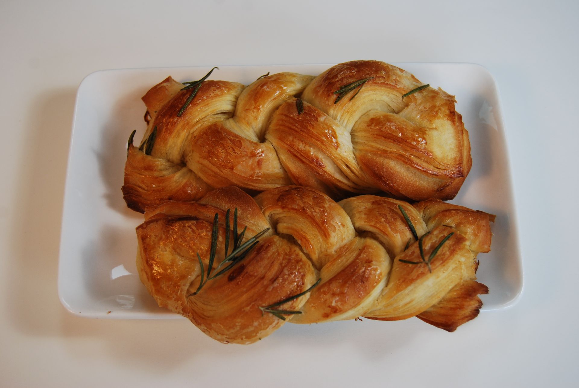 Two pieces of bread with rosemary on a white plate