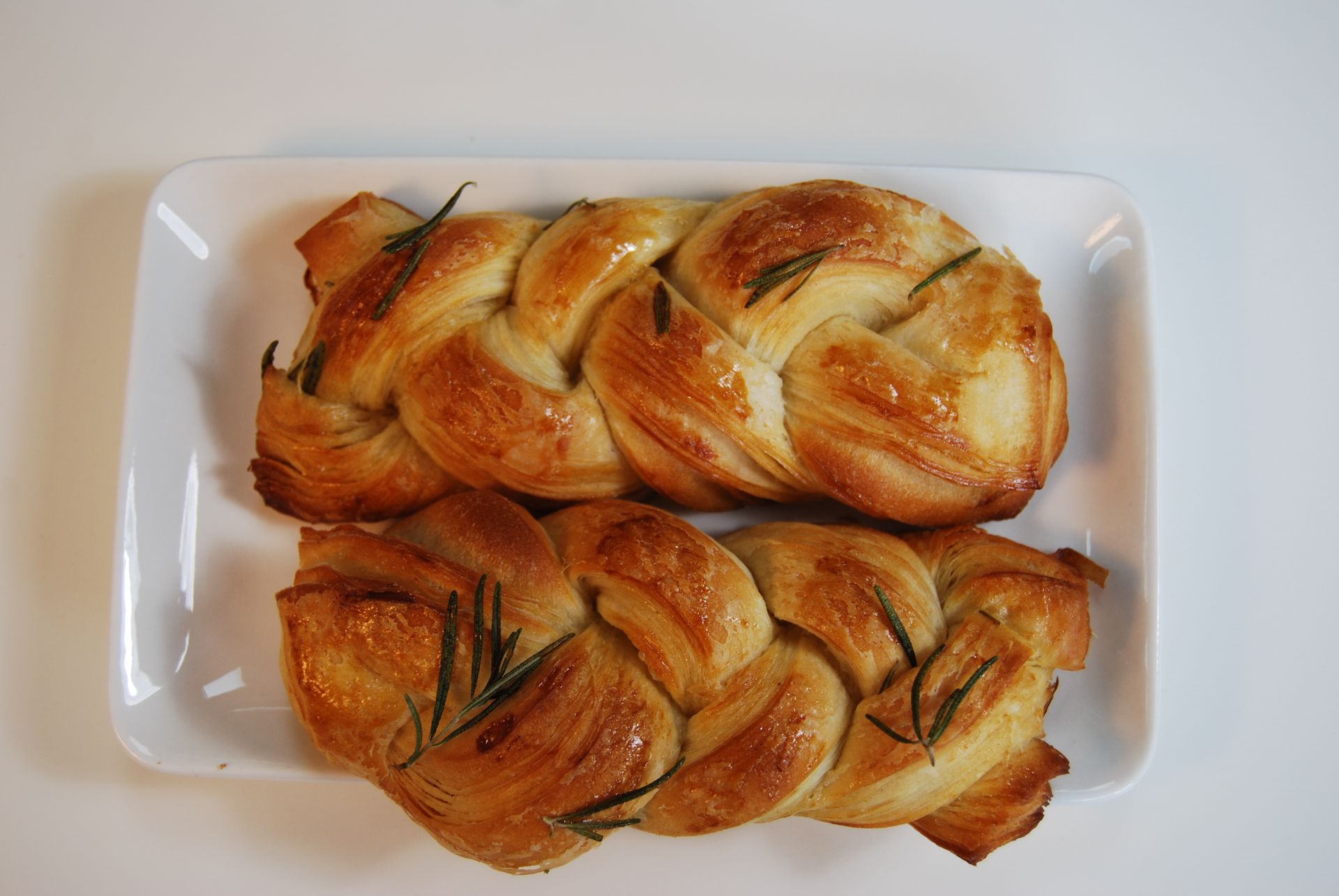 Two pieces of bread with rosemary on a white plate