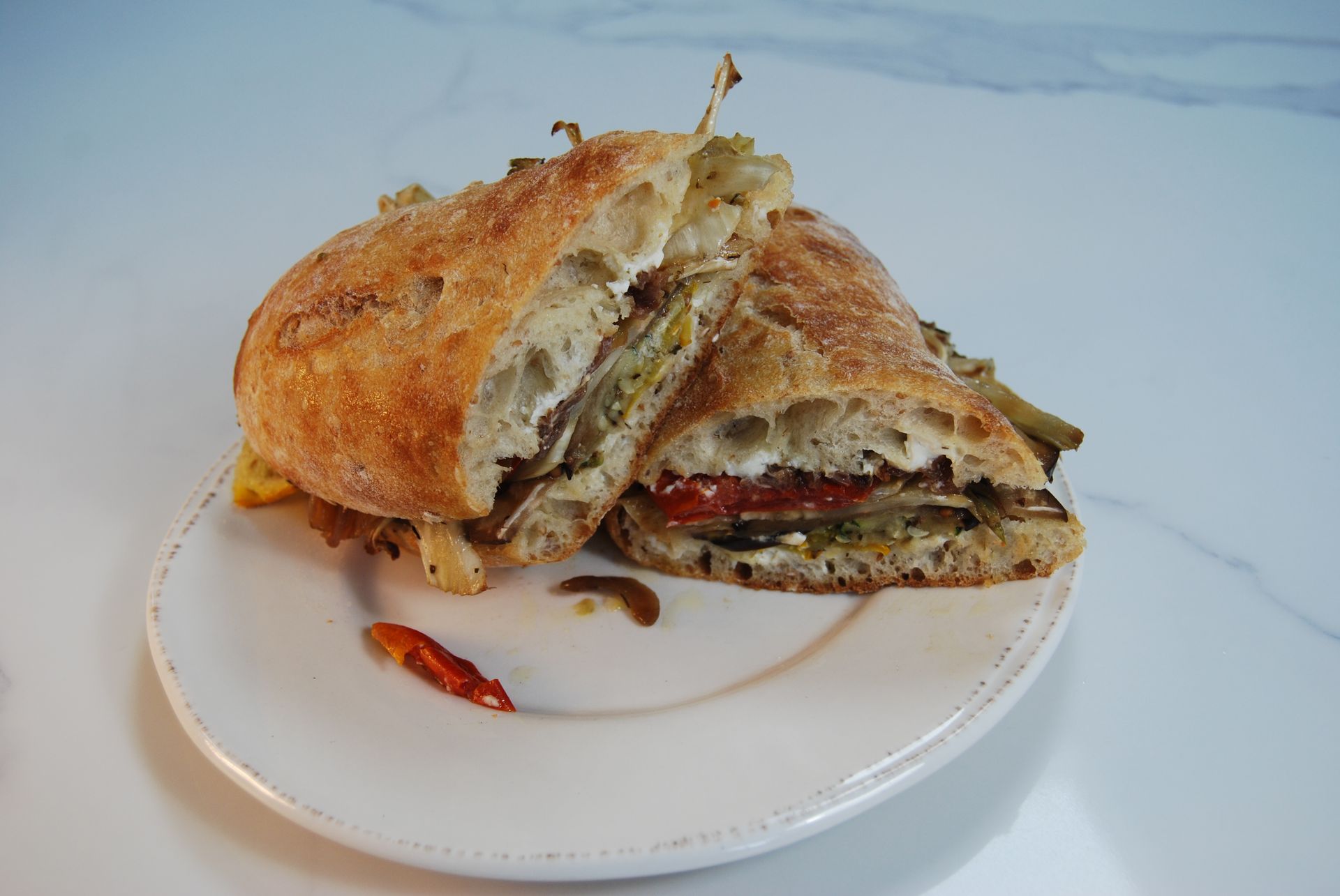 A sandwich is cut in half on a white plate