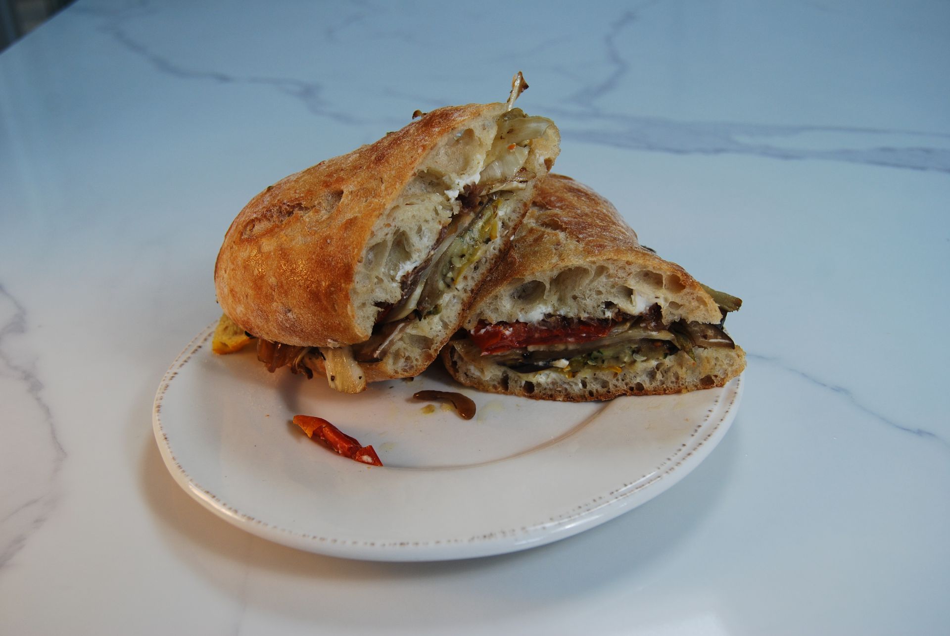 A sandwich is cut in half on a white plate