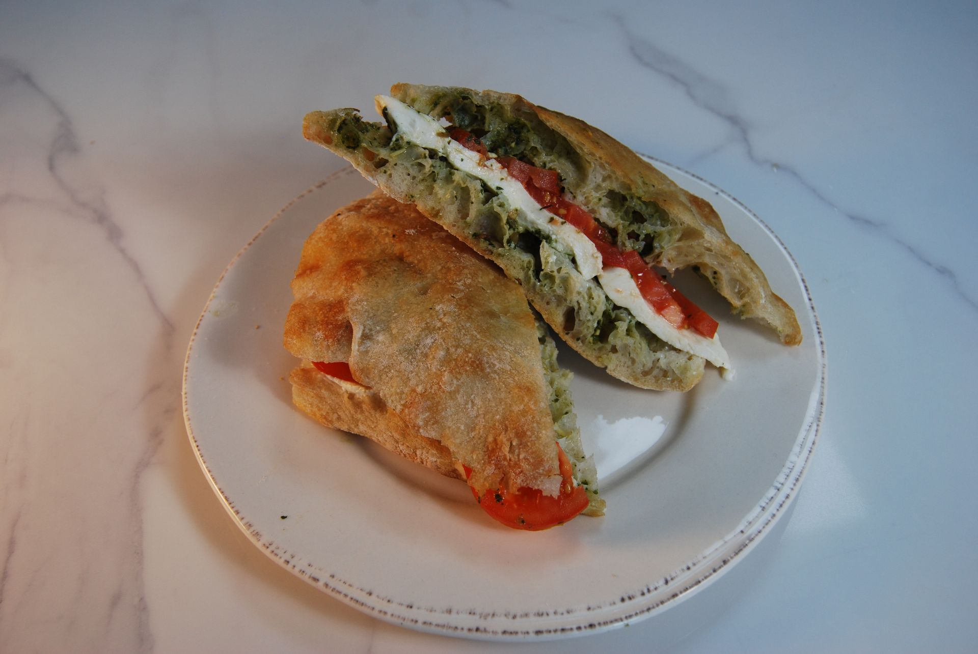 A white plate topped with a sandwich cut in half