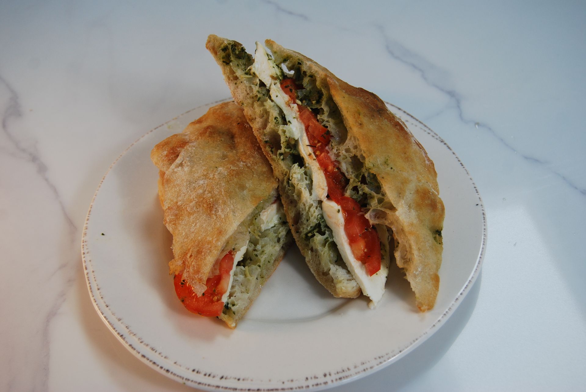 Two sandwiches are cut in half on a white plate