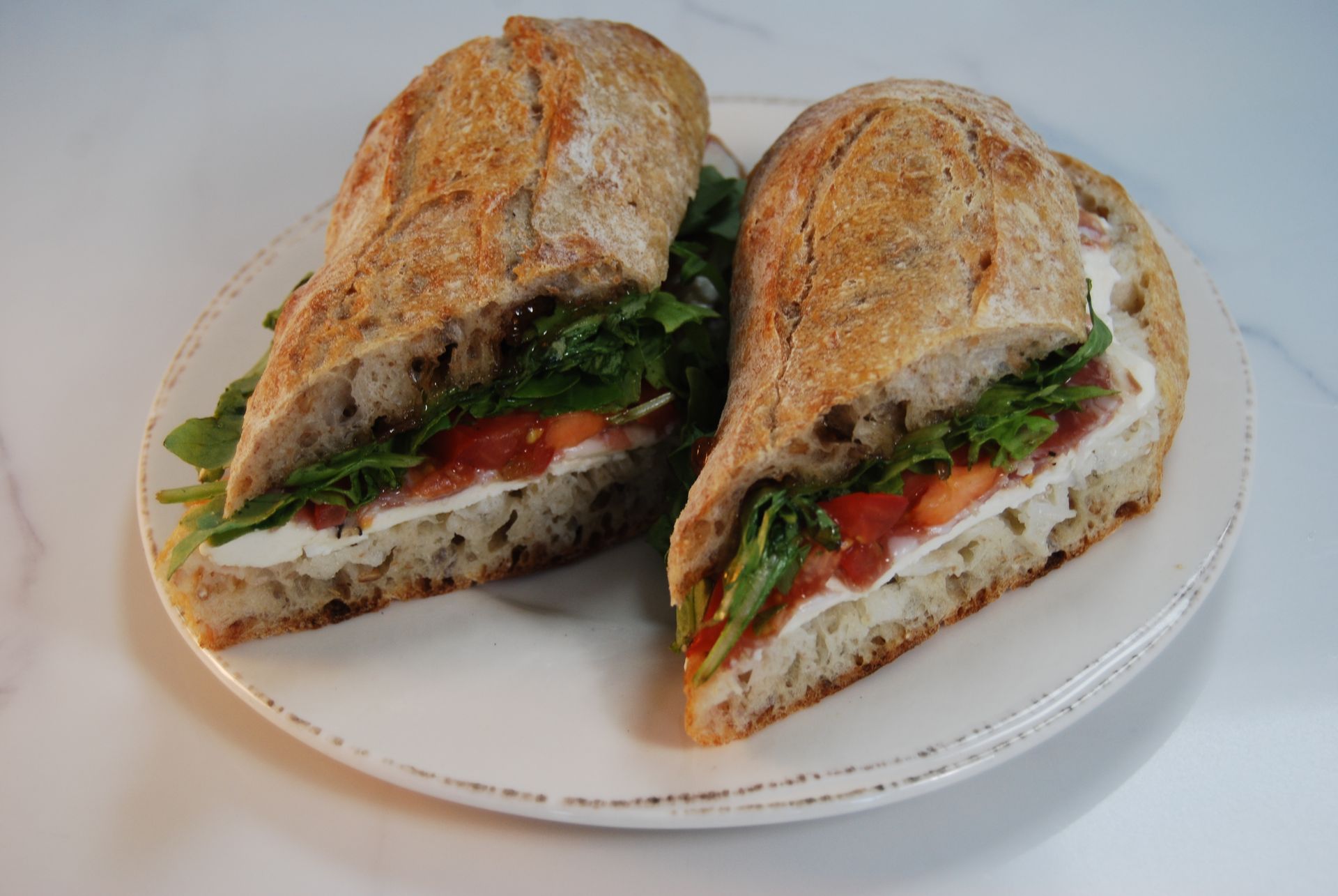 Two sandwiches are cut in half on a white plate