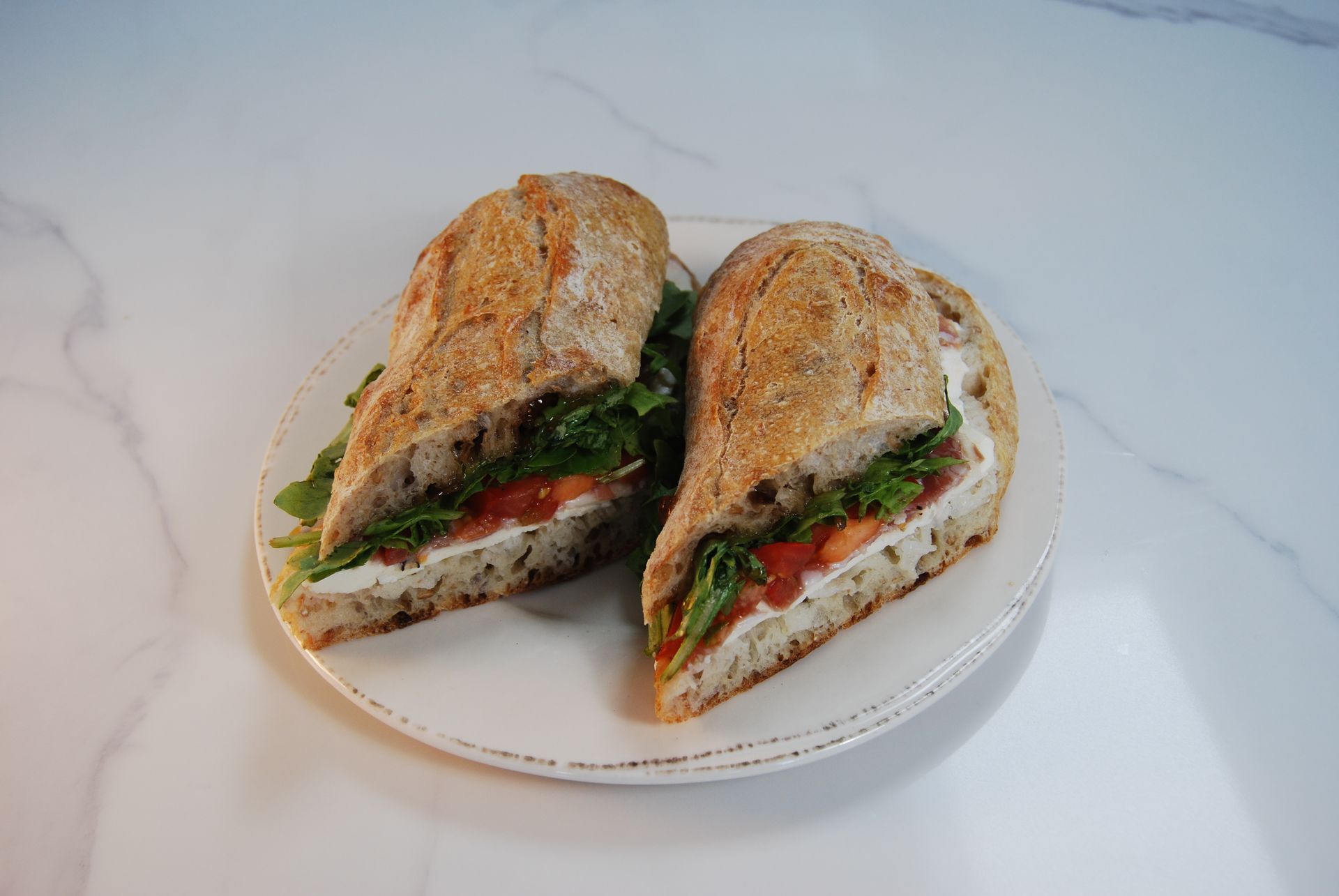 A sandwich is cut in half on a white plate