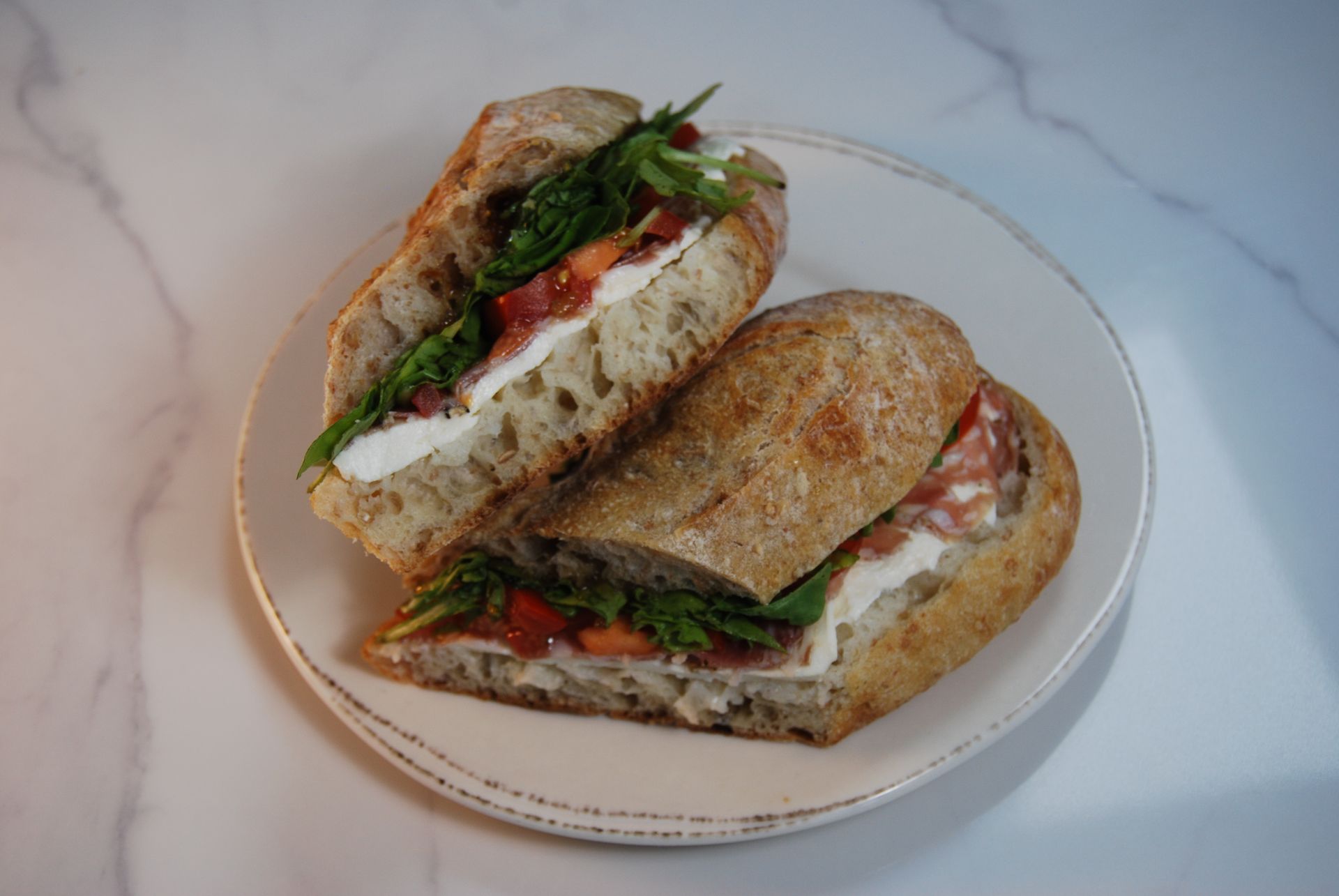 Two sandwiches are cut in half on a white plate