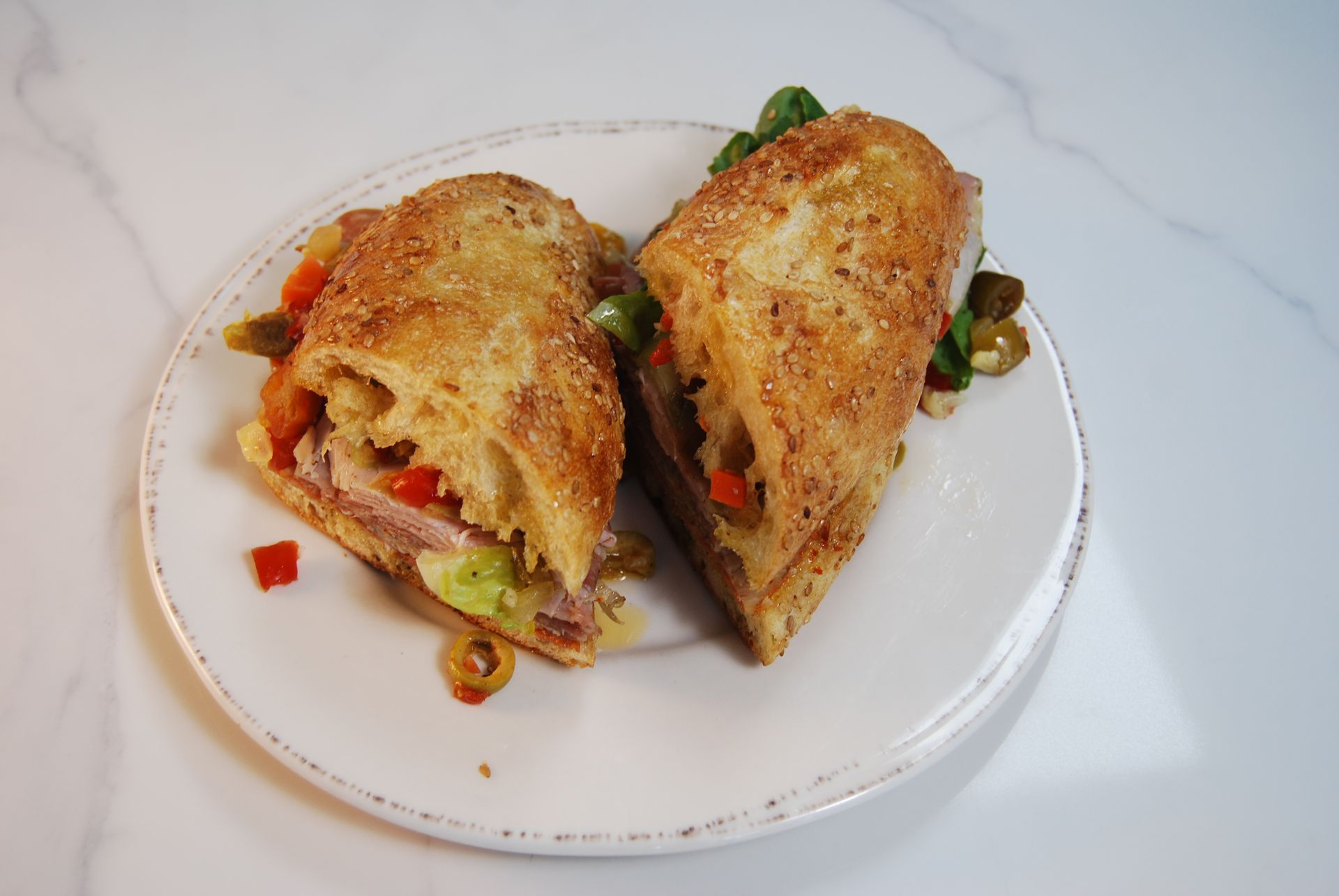 A sandwich is cut in half on a white plate