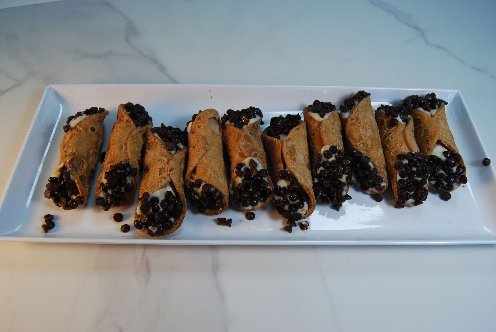 A tray of cannoli with chocolate chips on top