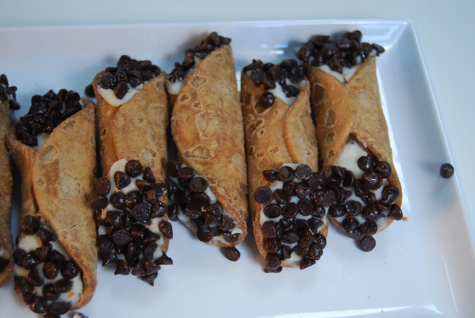 A white plate topped with cannoli filled with chocolate chips