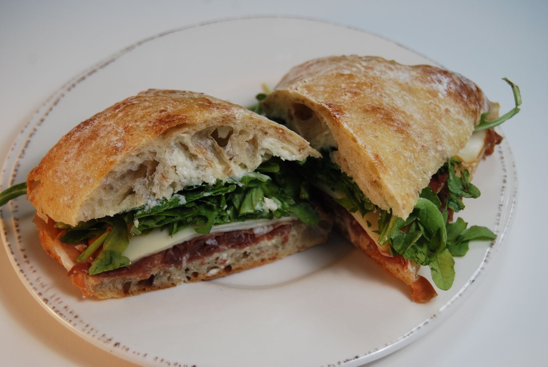 A sandwich is cut in half on a white plate