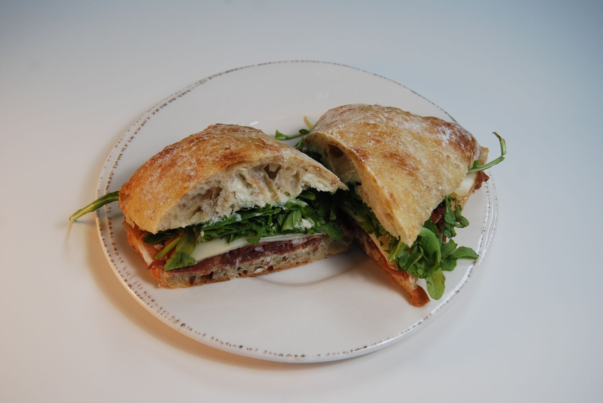 A sandwich is cut in half on a white plate