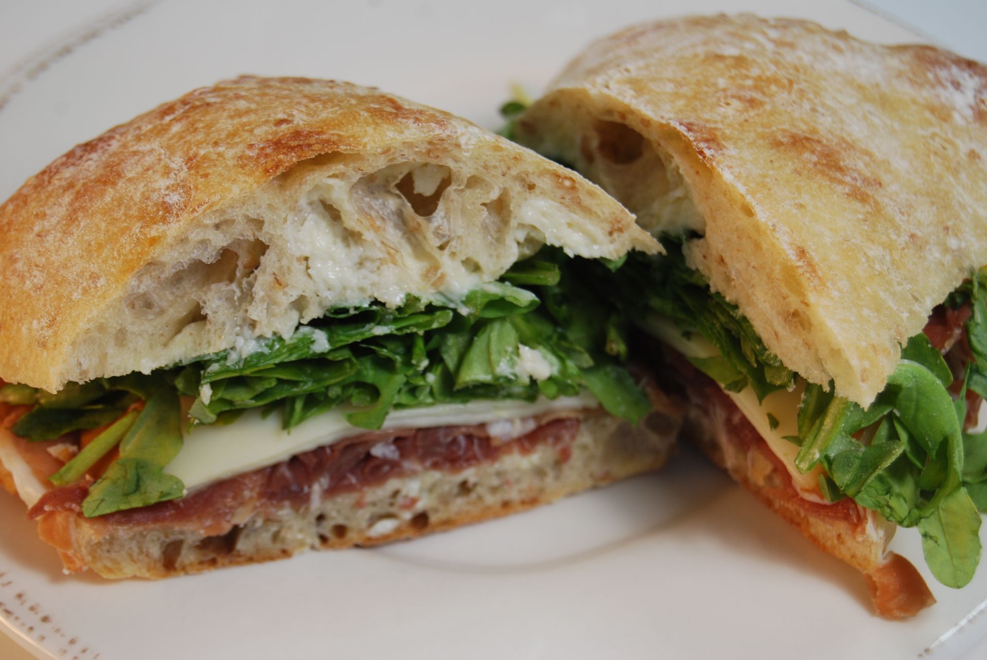 A sandwich is cut in half on a white plate