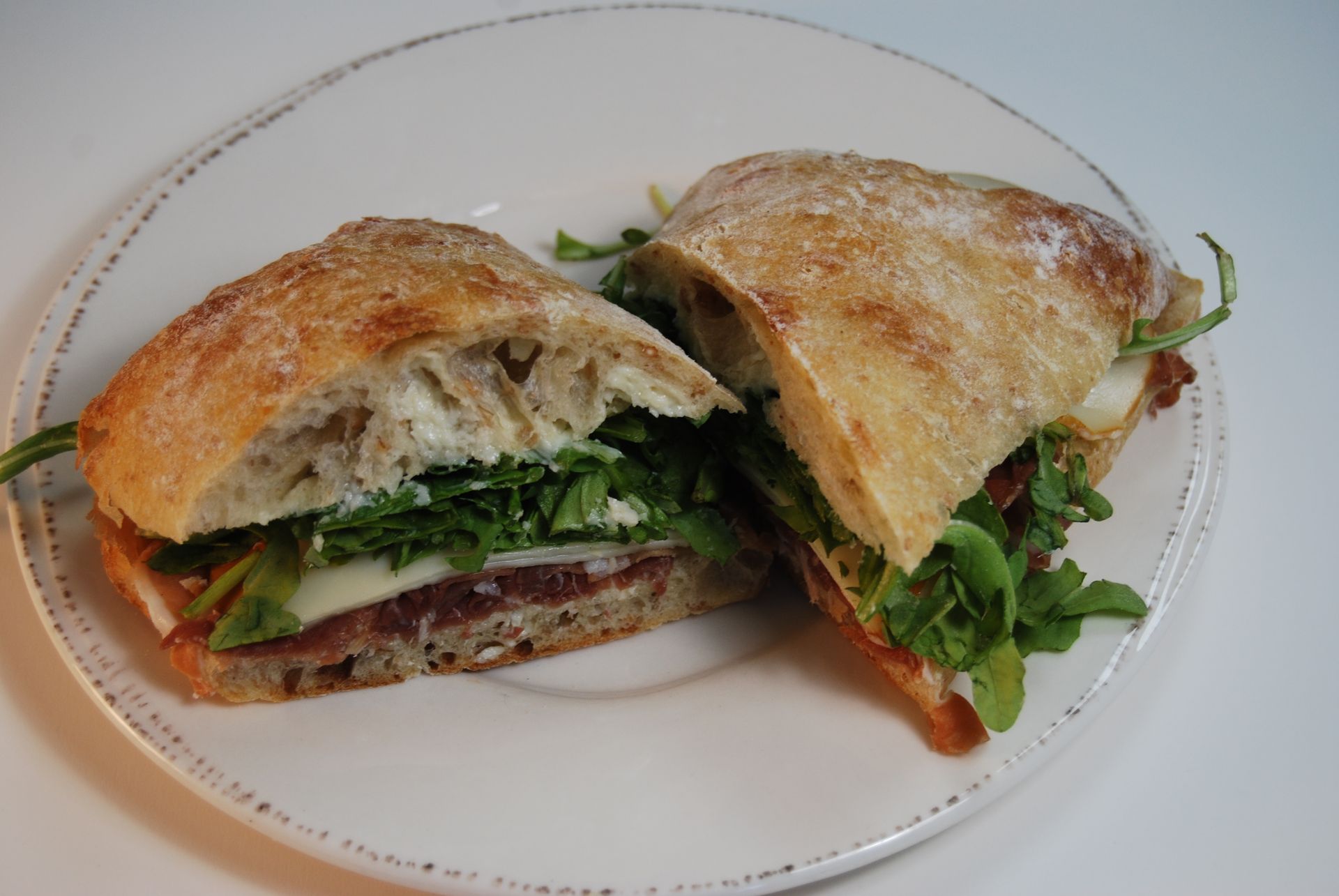 A sandwich is cut in half on a white plate