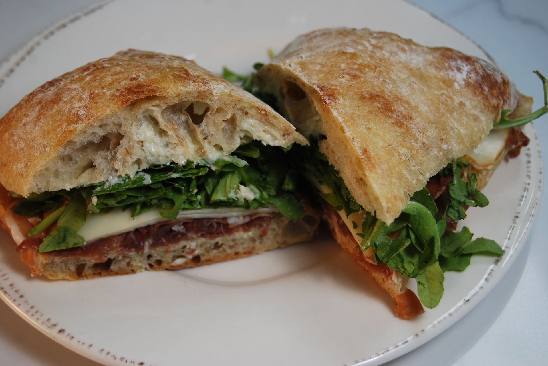 A sandwich is cut in half on a white plate