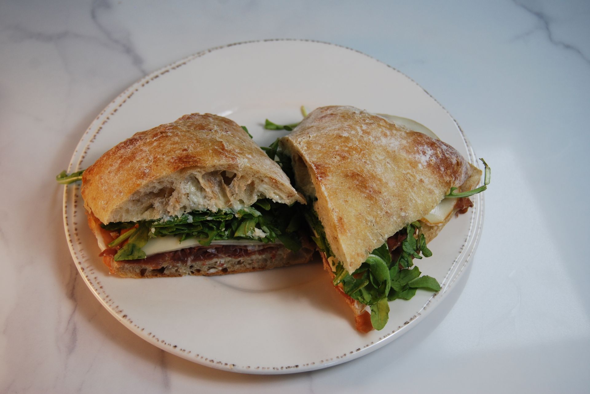 A sandwich is cut in half on a white plate