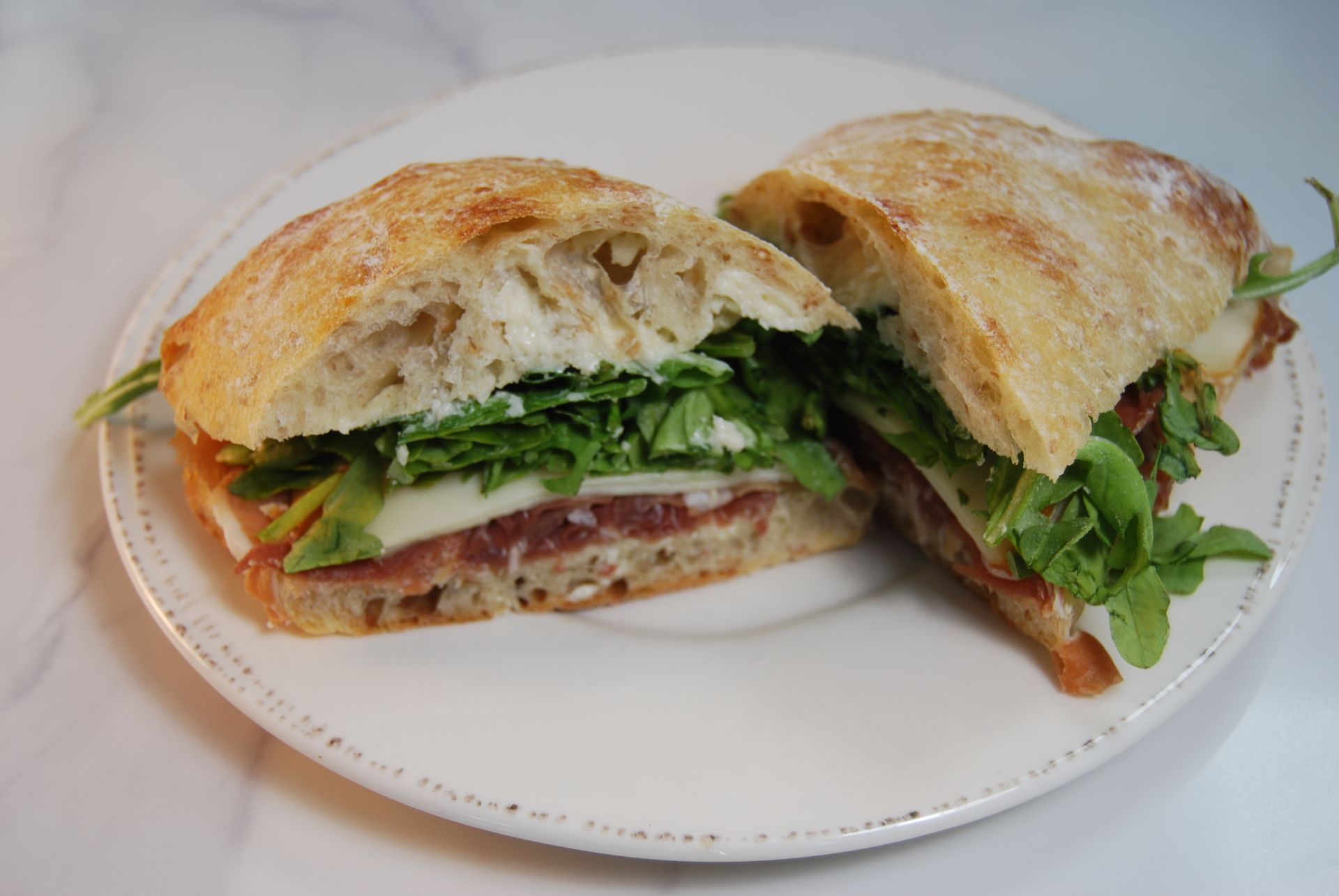 A sandwich is cut in half on a white plate