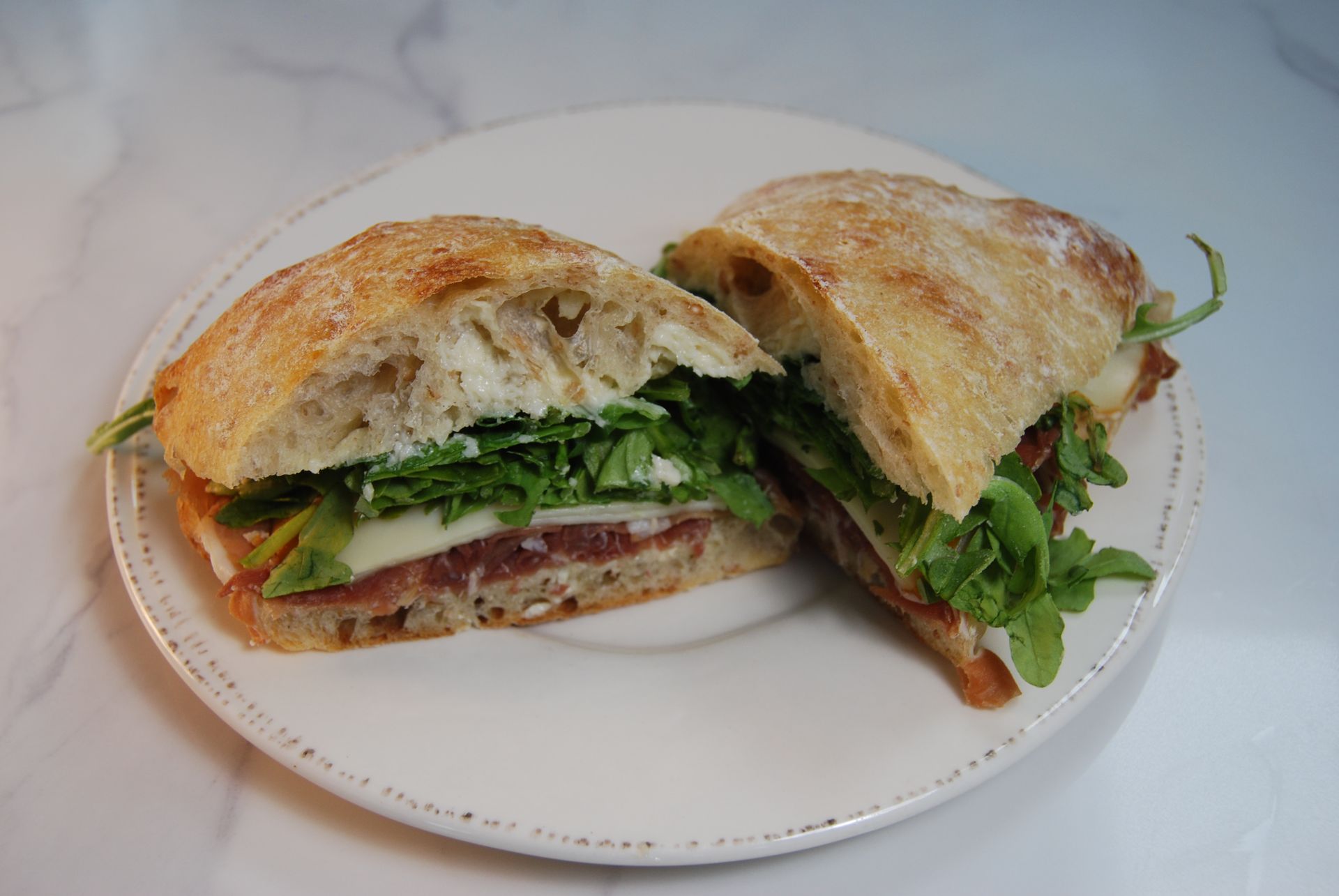 A sandwich is cut in half on a white plate