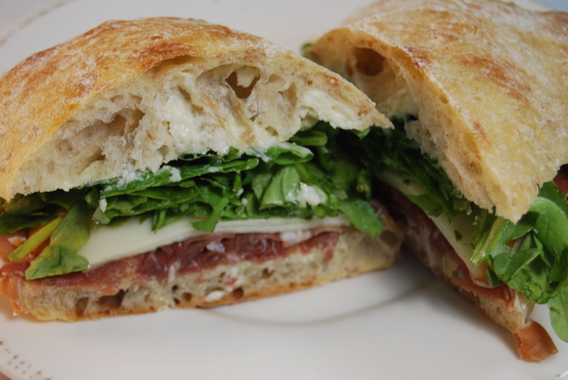 A sandwich is cut in half on a white plate