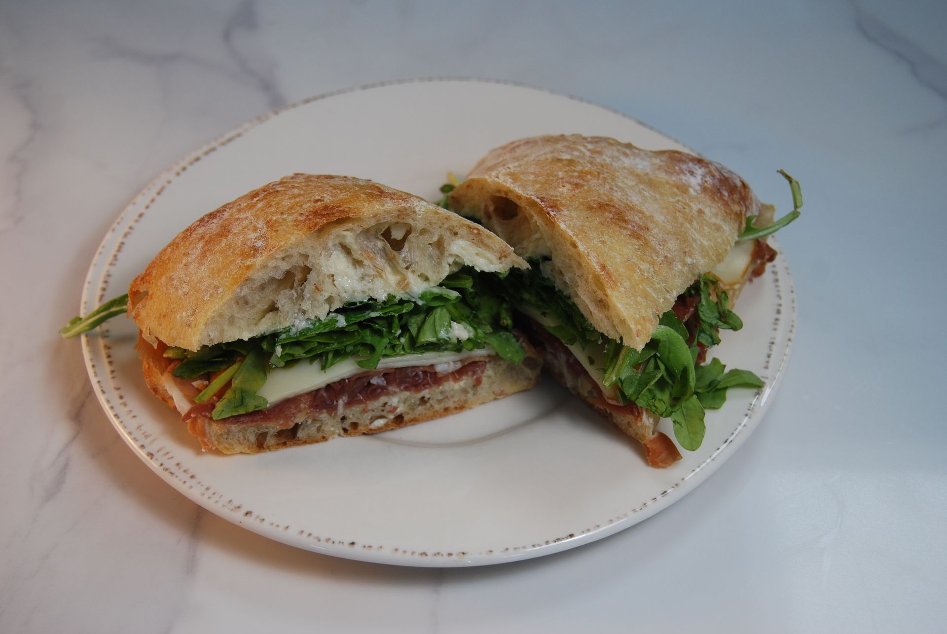 A sandwich is cut in half on a white plate