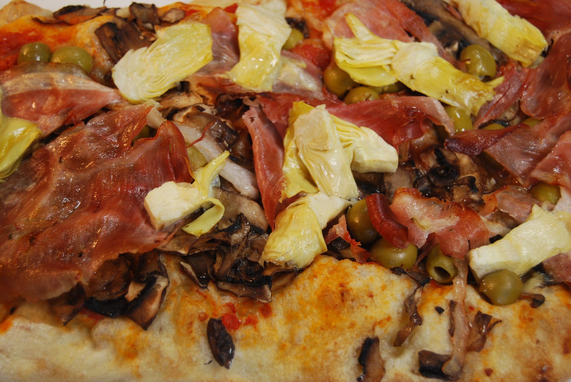 A pizza with artichokes mushrooms and bacon on it