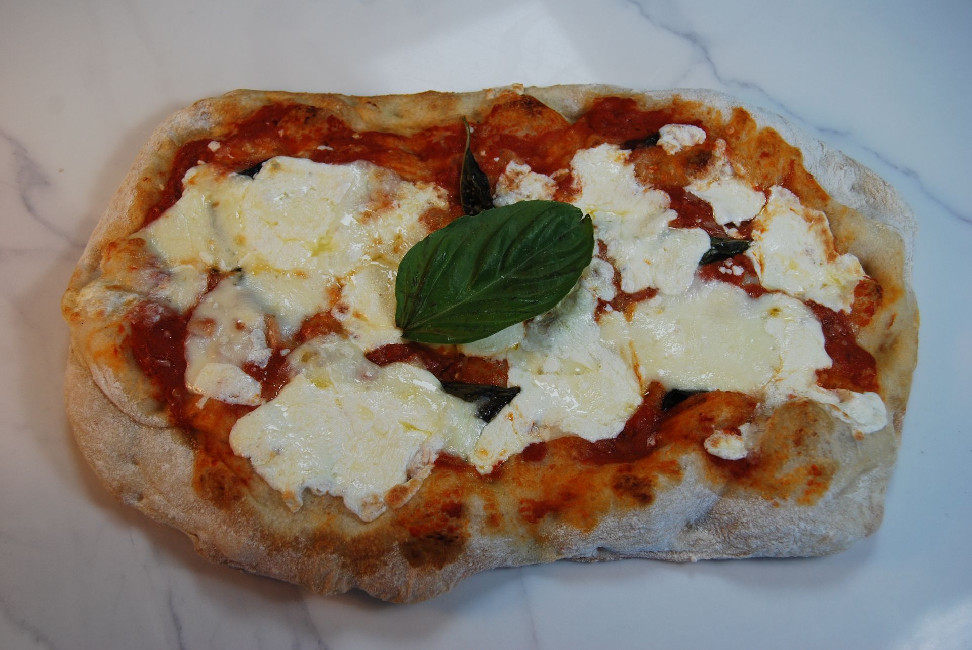 A pizza with a basil leaf on top of it