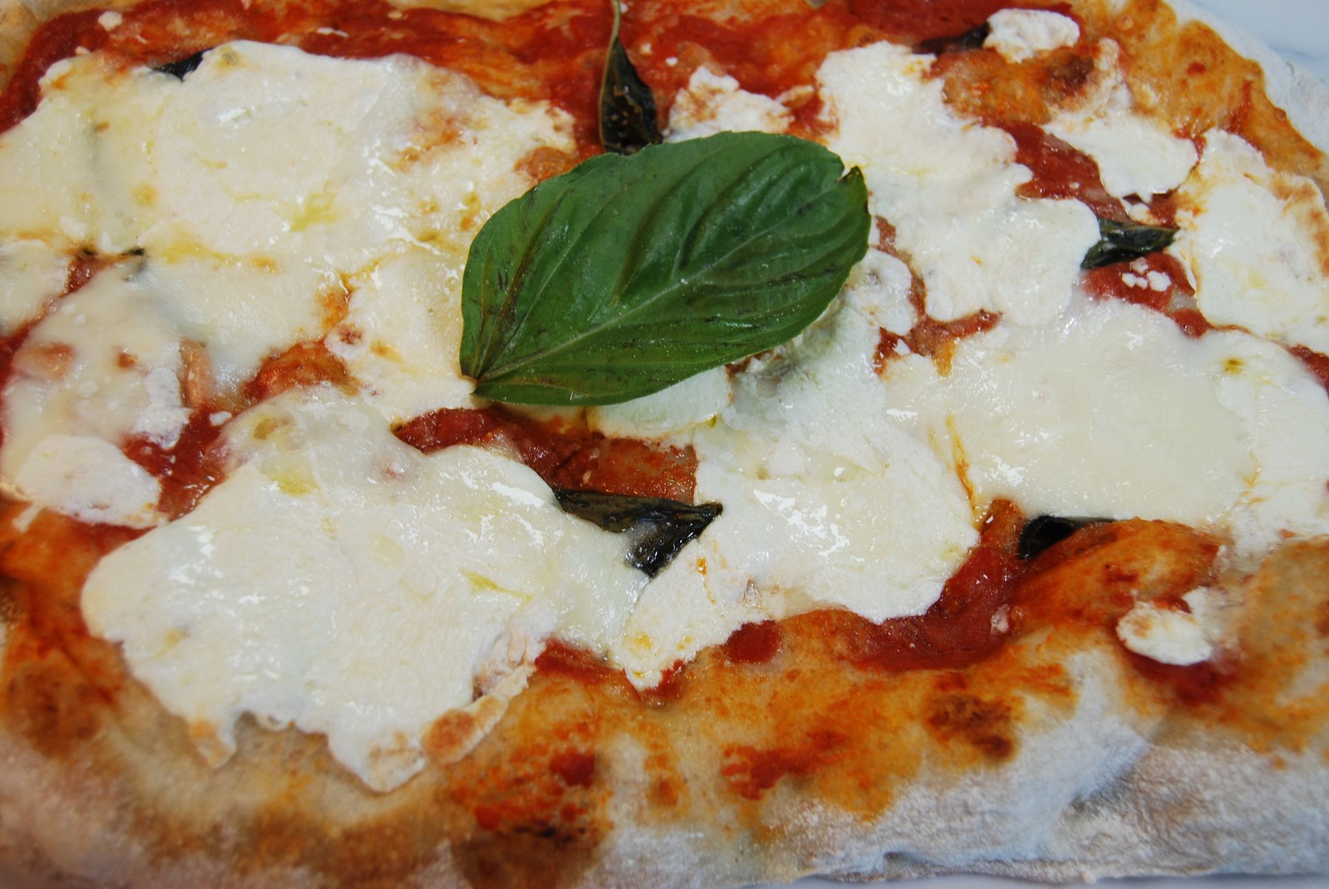 A pizza with a basil leaf on top of it