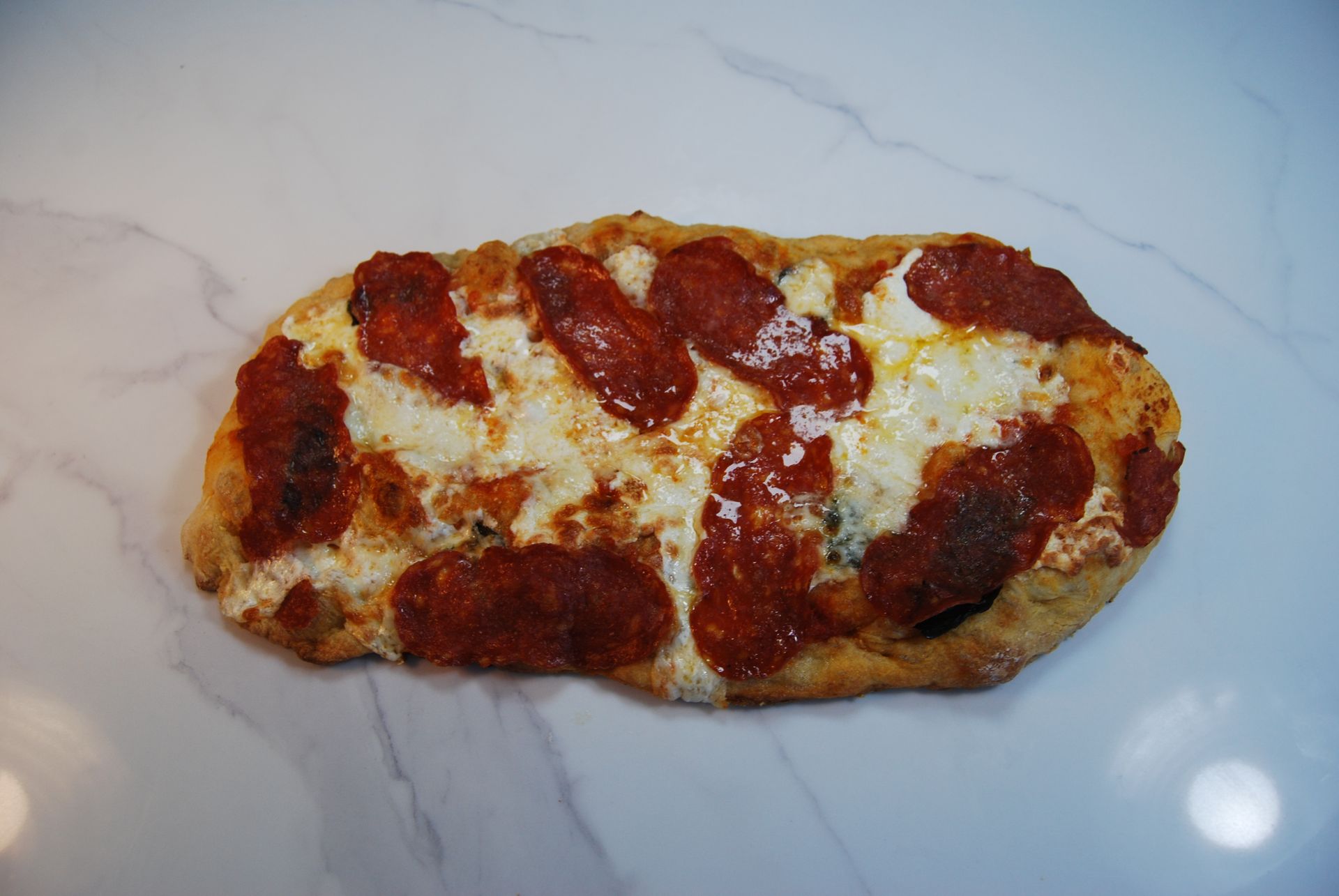 A pizza with pepperoni and cheese on a white surface