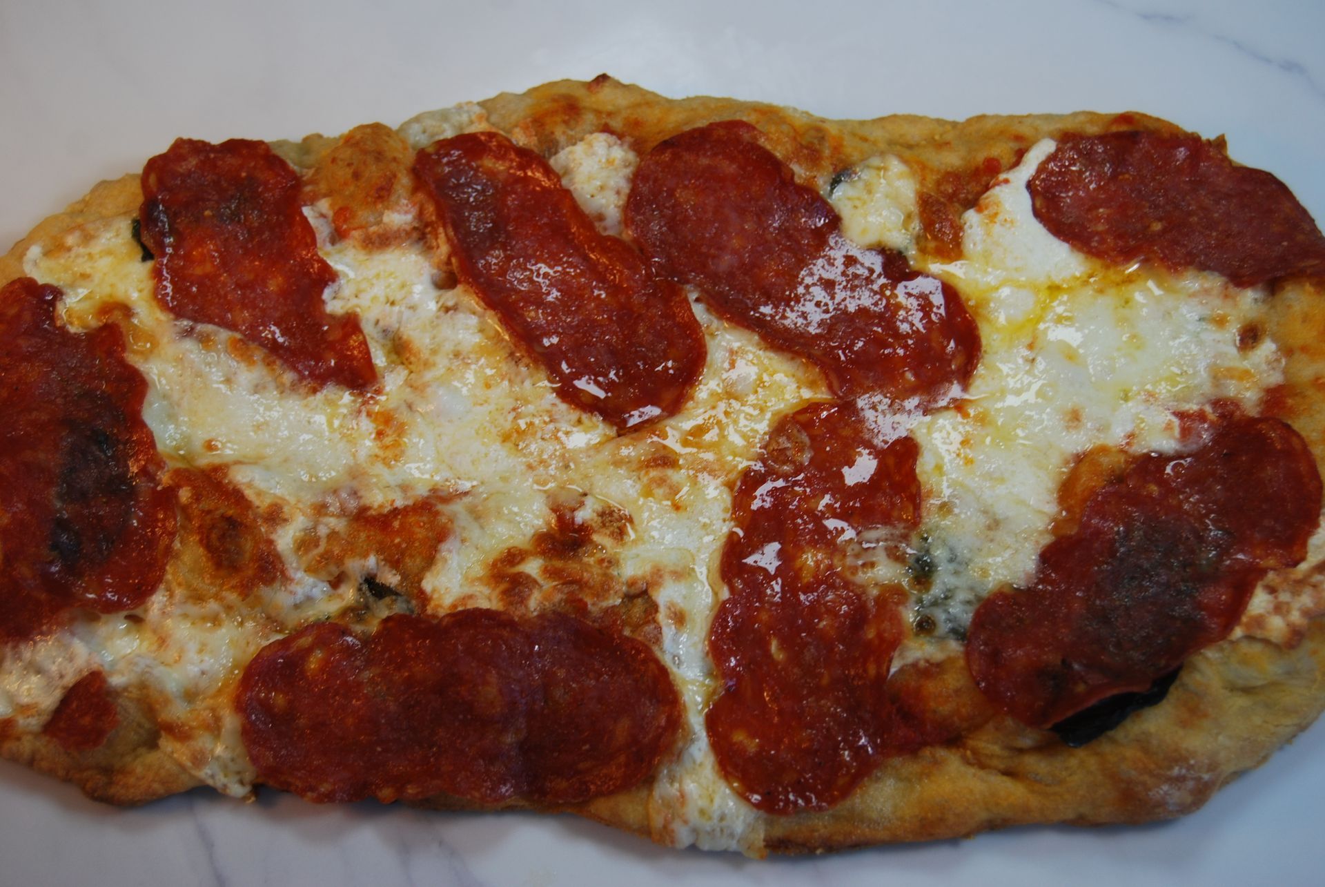 A pizza with pepperoni and cheese on a white plate