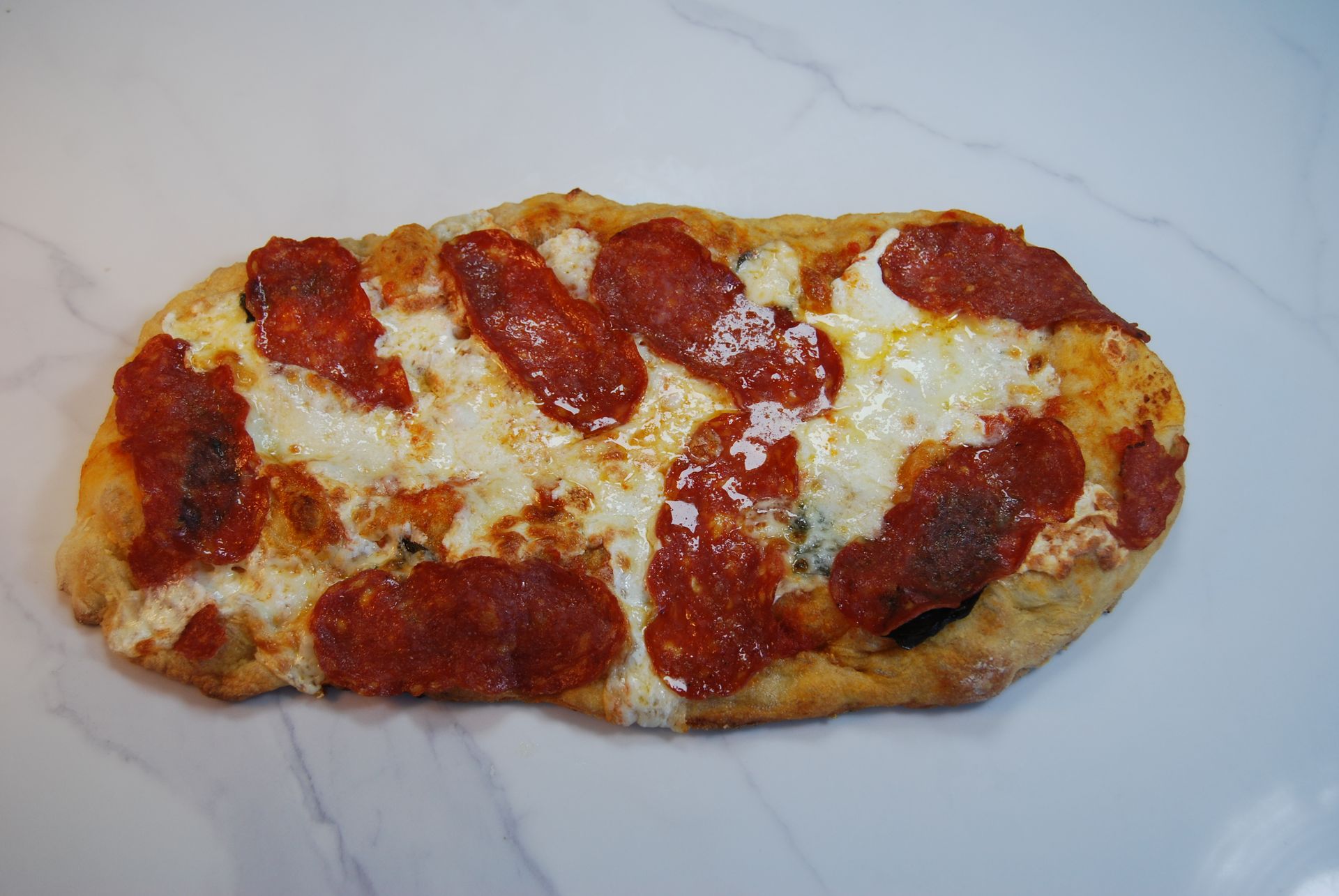 A pizza with pepperoni and cheese on a white surface