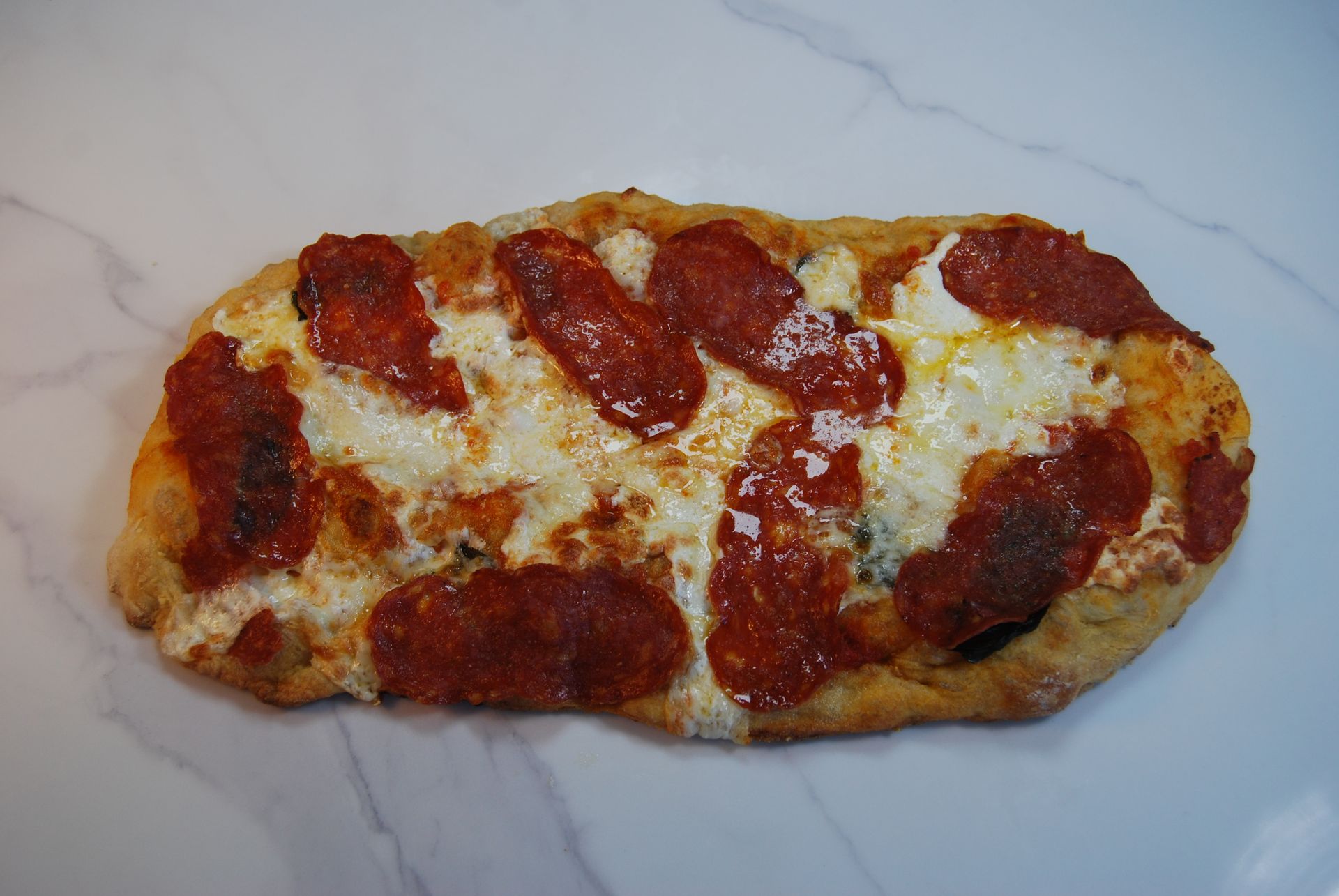 A pizza with pepperoni and cheese on a white surface