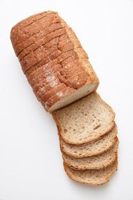 A loaf of bread is cut into slices on a white surface.